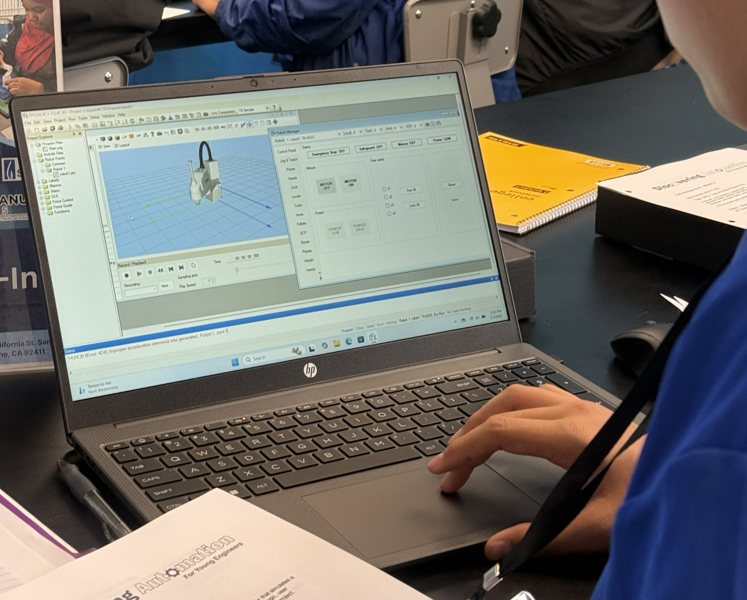A DAYP student programming an Epson robot in the Epson RC+ 3D simulation environment on a laptop