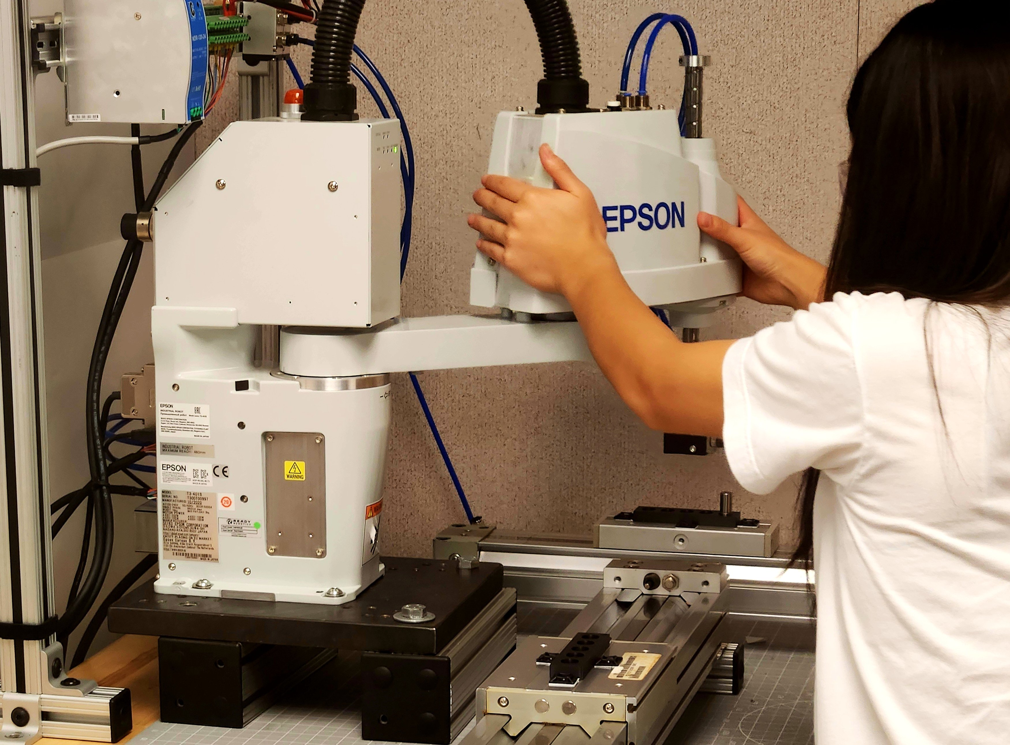A DAYP student working hands-on with a physical Epson SCARA robot cell in the AAI lab